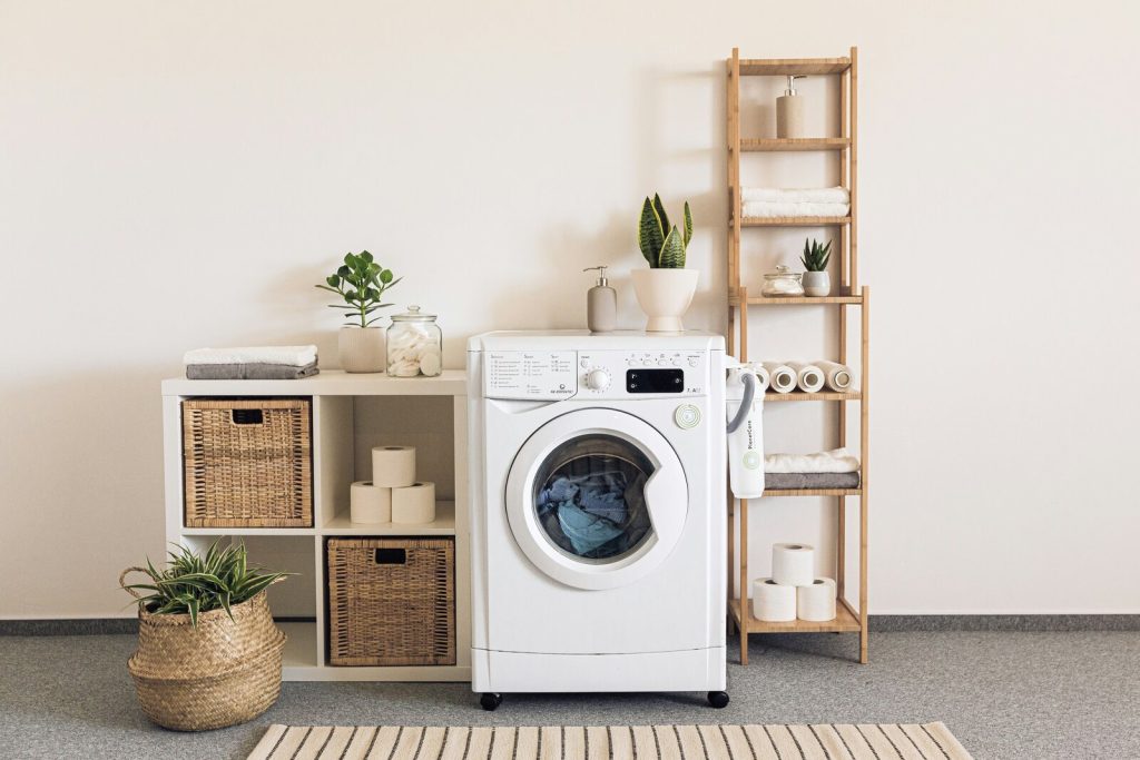 washing machine against a white wall with wooden shelves of different sizes next to it